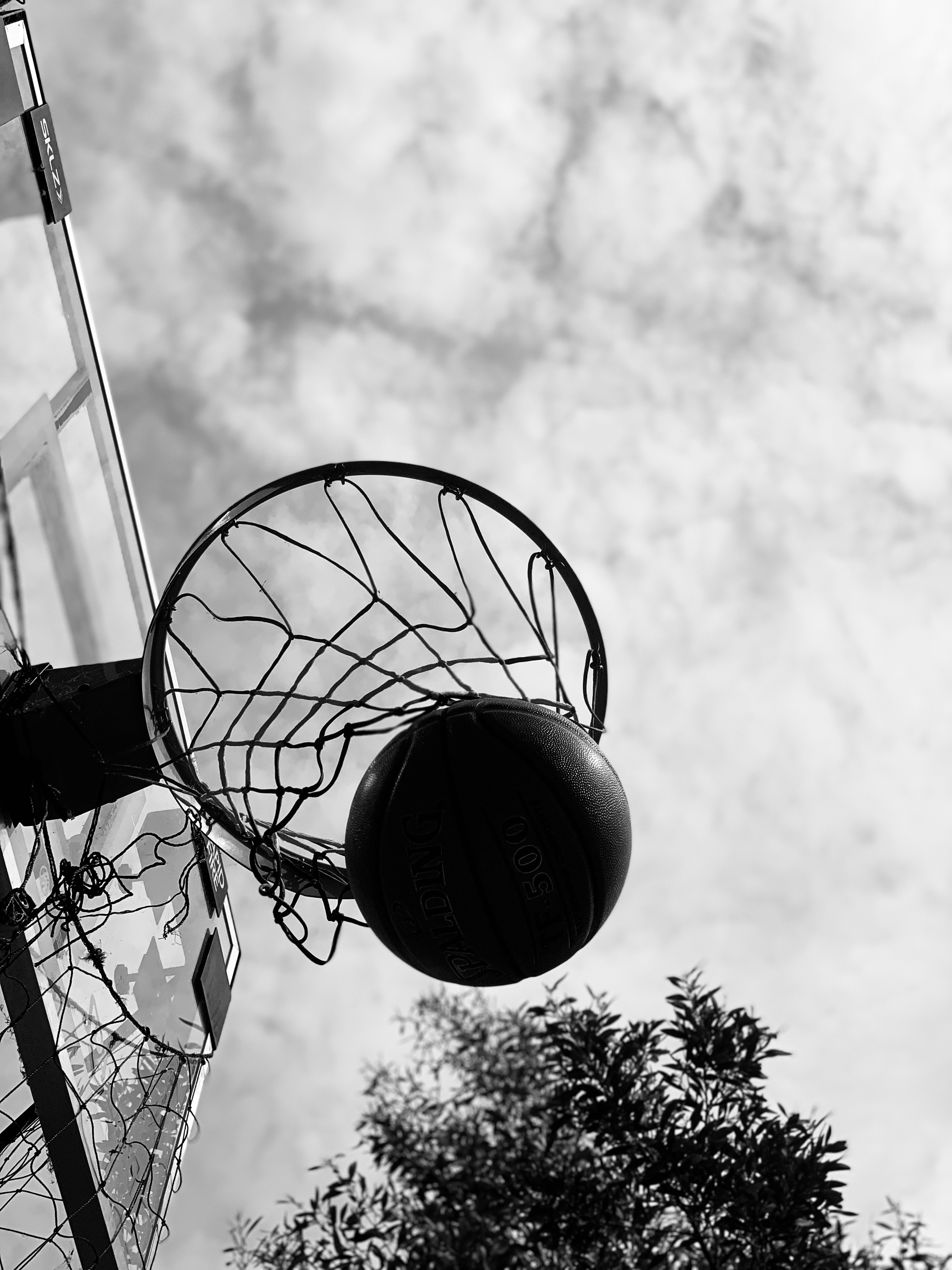 B&W picture of basketball leaving net of basketball hoop